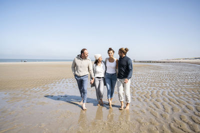People on beach against clear sky