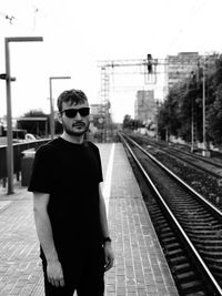 Portrait of young man standing against railroad station platform