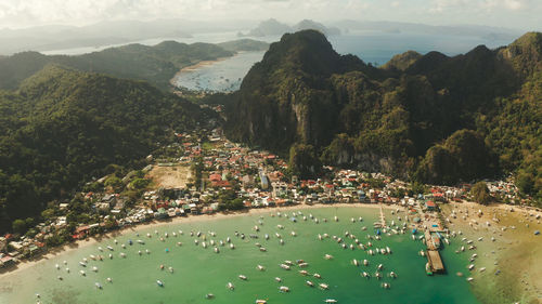 Town el nido on the coast with bay and lot tourist boats, palawan, philippines aerial view. 