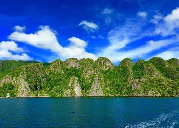 Scenic view of sea and mountains against blue sky