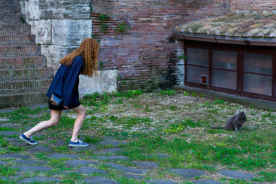 Full length side view of woman walking against building