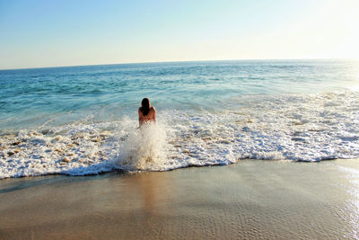 Waves splashing on woman standing on shore