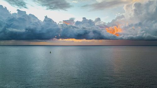 Scenic view of sea, ship and red clouds  against sky