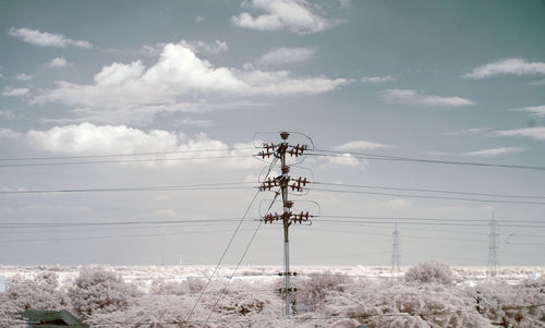 Power lines against cloudy sky