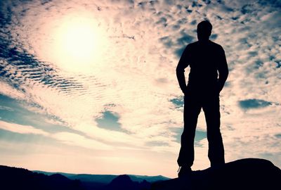 Hiker stand on sharp corner of sandstone rock in rock empires park and watching over valley to sun