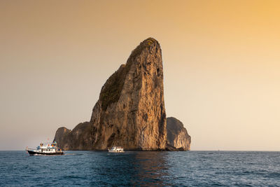 Scenic view of rock formation in sea against clear sky