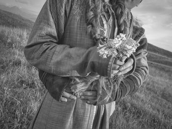 Close-up of person holding flower standing on field