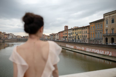 Rear view of woman standing against canal in city
