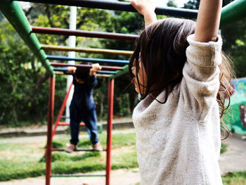 Low angle view of girl and boy playing on monkey bars at playground