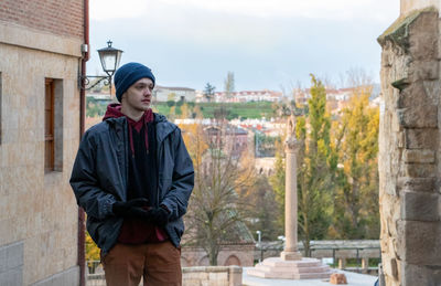 Thoughtful teenage boy wearing jacket standing outdoors