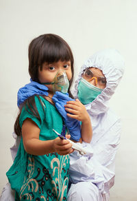 Portrait of doctor with girl wearing mask against white background