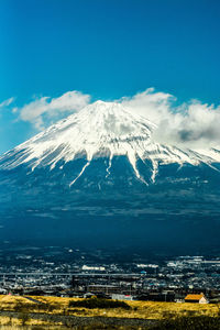 Aerial view of snowcapped mountain against blue sky