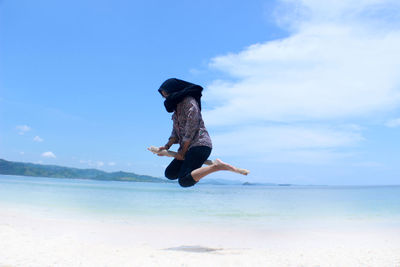 Low angle view of man jumping on beach against sky