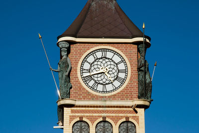 Low angle view of clock tower against clear blue sky