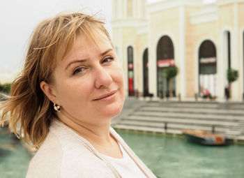 Close-up portrait of mature woman against canal in city