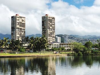 Buildings by lake against sky in city