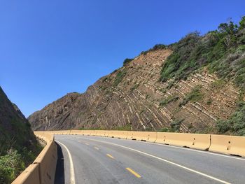 Road by mountains against clear blue sky