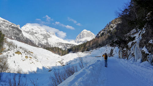 Man hiking on snow coveres road in mountains.