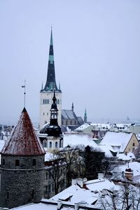 Tower amidst buildings against sky during winter