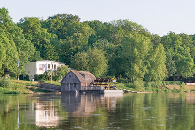 Scenic view of lake by trees and building against sky