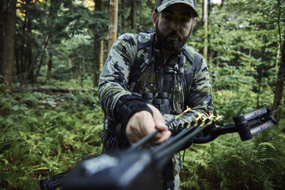 Young man holding camera in forest