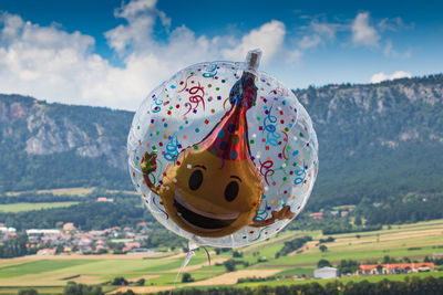 High angle view of balloons on field against cloudy sky