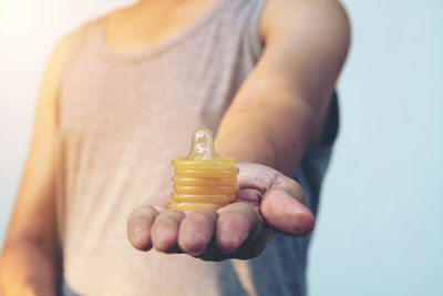 Midsection of man with condoms against sky