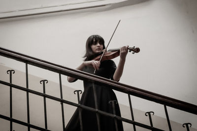 Full length of young woman playing violin