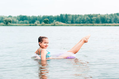 A cheerful girl swims on an inflatable ring in the river and stretches her legs. local tourism. 