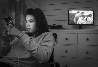 Teenage girl using phone while sitting at home