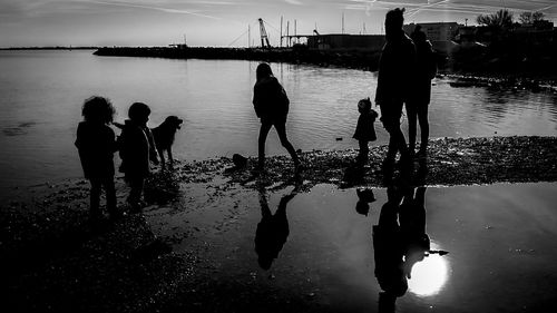 Silhouette people on sea against sky