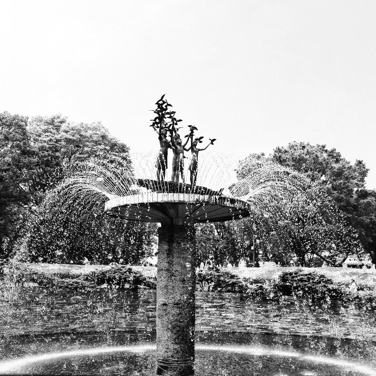 low angle view, clear sky, tree, art and craft, sculpture, art, statue, human representation, creativity, sky, day, copy space, outdoors, built structure, animal representation, growth, no people, nature, architecture