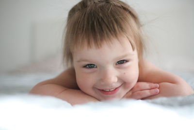 Happy funny girl toddler lifestyle with a smile lying on the bed, close-up, 