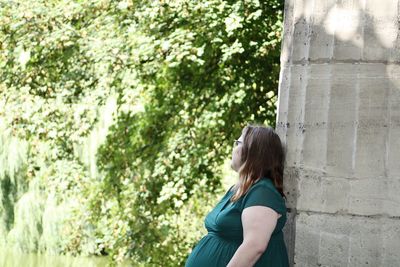 Side view of woman leaning on built structure