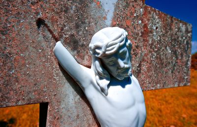 Close-up of broken jesus christ statue on cross