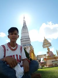 Man sitting against sky in city