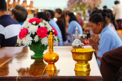 Religious offerings on table by people and monks praying in temple