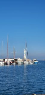 Sailboats sailing on sea against clear blue sky
