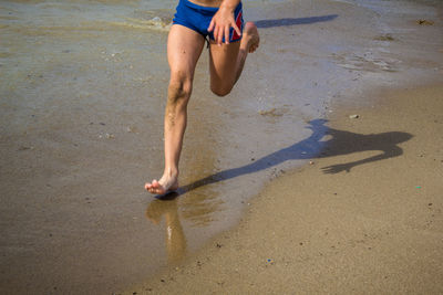 Low section of person on wet sand at beach