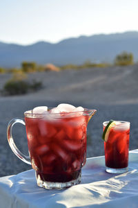 Pitcher and drink glasses of hibiscus flower iced tea in mojave desert setting