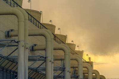 Low angle view of factory against sky during sunset