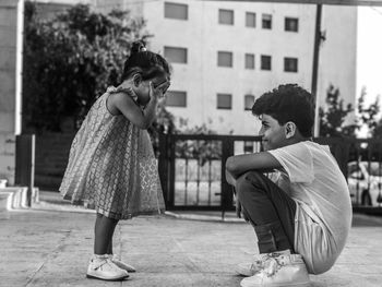 Full length of siblings playing on footpath