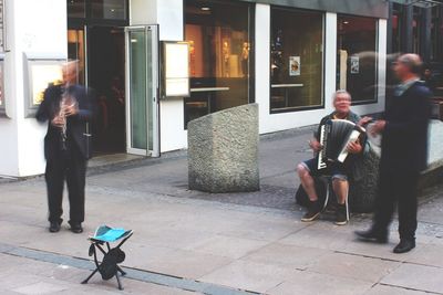 People sitting on sidewalk in city