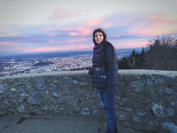 Portrait of smiling young woman standing against sky during sunset