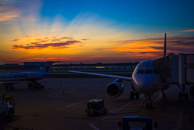 Airplane on runway against sky during sunset