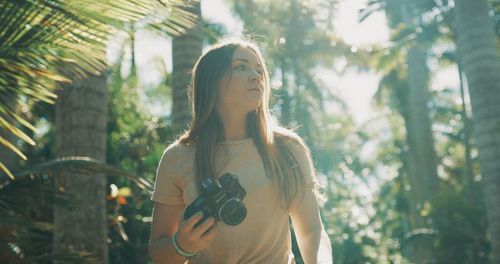 Young woman standing against trees