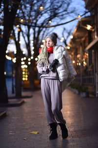 Woman in warm clothes while standing on sidewalk in city