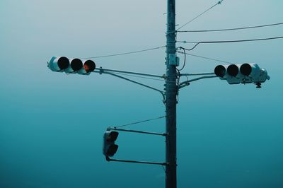 Low angle view of telephone pole against clear blue sky