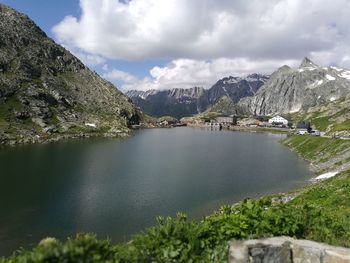 Scenic view of lake by mountain range against cloudy sky