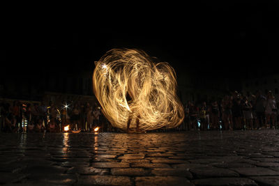 People at illuminated park against sky at night